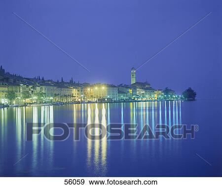 Town at the waterfront lit up at night View Large Photo Image Stock Photo - Town at the waterfront lit up at night . Fotosearch