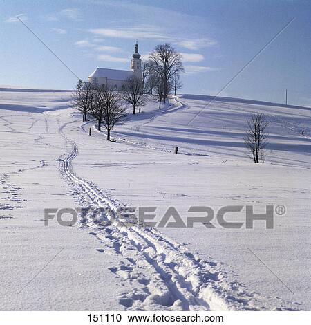 Stock Image - Trail on snow covered landscape leading to church, Upper Palatinate, Bavaria, Germany . Fotosearch