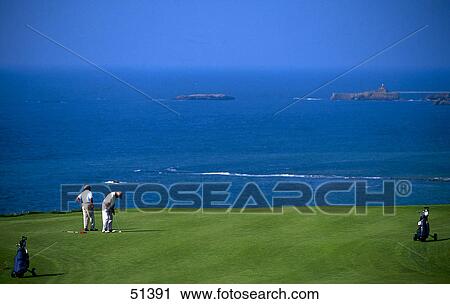 Stock Image - Two men playing golf on golf course, Capbreton, France . Fotosearch