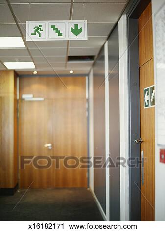 Fire Exit Sign Suspended From The Ceiling In An Office Stock Image