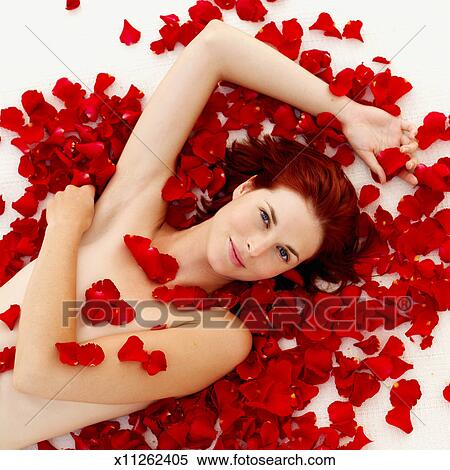 Elevated view of a nude woman covered in rose petals Stock 