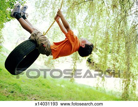 Stock Photo of Boy (6-8) playing on tire swing, side view x14031193 ...