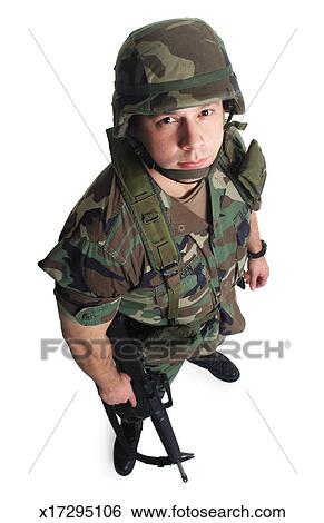 A caucasian male soldier in fatigues and holding a gun looks sternly up ...