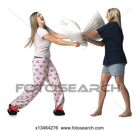 Two Caucasian Blonde Female Teens Dressed In Pajamas Have A Pillow