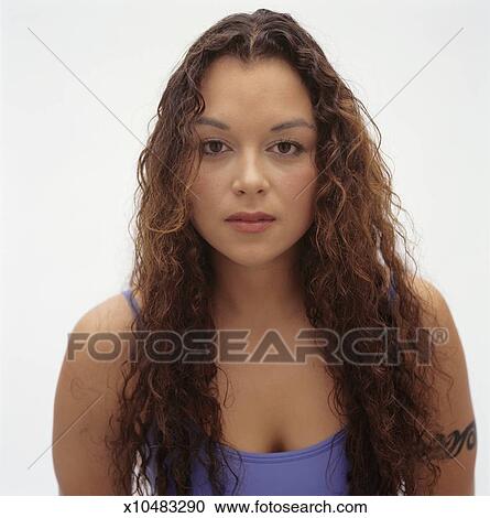 Young Woman With Long Brown Curly Hair And Tattoo On Arm Posing In