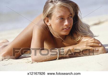 Young Woman Lying Naked On Sandy Beach Stock Photograph