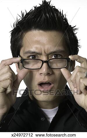 Man With Spiky Hair In Studio Holding Glasses Down And Looking