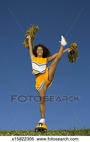 Female cheerleader doing high kick on football helmet Stock Photography