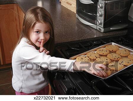An adorable 5 year old little girl stealing a chocolate chip cookie. Stock Image | x22732021