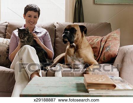 Young Woman Sitting On Couch With Dog And Cat Stock Photo
