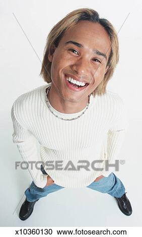 A Handsome Young Asian Man With Bleached Hair Stands Looking Up At