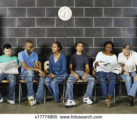 stock image of group of students sitting reading newspapers talking