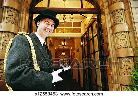 Doorman Gesturing Towards A Hotel Entrance Stock Image X12553453