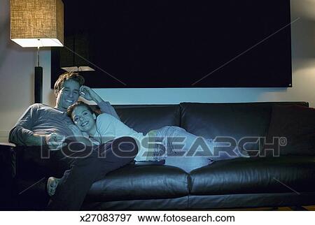 Picture - Couple Relax on a Leather Sofa at Night, Watching TV and Smiling. Fotosearch - Search Stock Photography, Photos, Prints, Images, and Photo Clipart