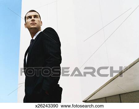 Low Angle Shot Of A Businessman Standing By A Building With His