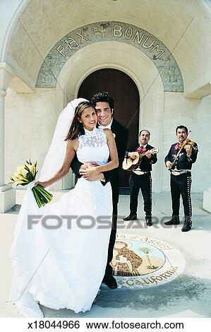 Bride And Groom Stand Outside A Church With A Mariachi Band