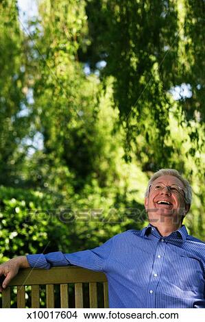 Senior Man Sitting On Garden Bench Smiling Picture X10017604