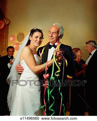 Bride Dancing With Mature Male Guest At Wedding Reception