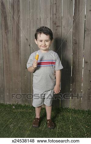 Download Boy (2-4) eating popsicle in front of fence, portrait ... Yellowimages Mockups