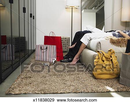 Couple Lying On Bed Shopping Bags On Floor Side View Low