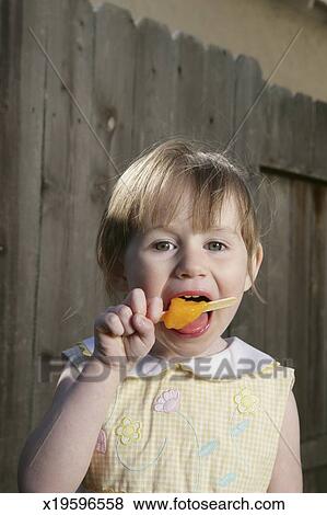 Download Girl (2-4) eating popsicle in front of fence, portrait ... Yellowimages Mockups