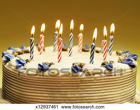 Nine Lit Candles And Blue Decorative Flowers On Birthday Cake