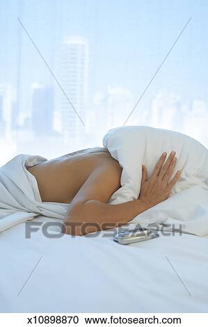 Woman Lying In Bed With Pillow Over Head City In Background Stock