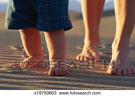 Fusse Von Baby Und Ausgewachsene Gehende Sand Stock Bild