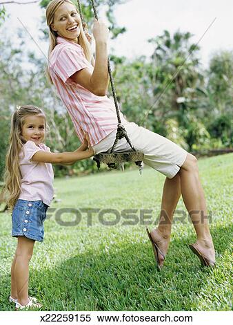 Side Profile Of A Girl Pushing Her Mother In A Swing Stock Photography