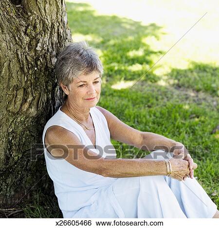 Elevated view of an elderly woman sitting against a tree Stock ...