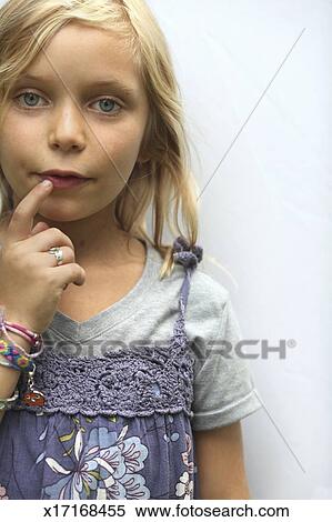 A Young Girl With Blonde Hair And Blue Eyes Her Hand To Her