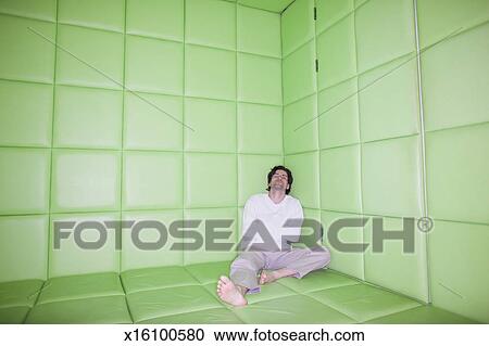 Man Sitting With Legs Apart In Padded Room Stock Image