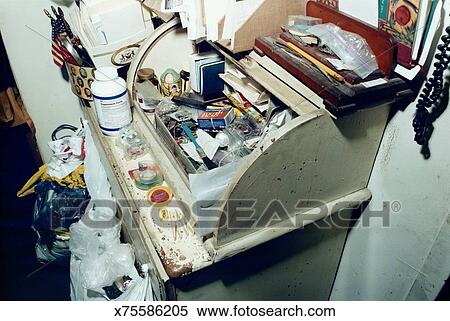 Cluttered Desk Top With Plastic Bags Hanging From Drawer Knobs