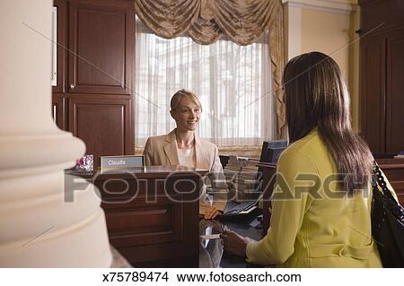 Woman At Bank Counter Conversing With Teller Picture X75789474