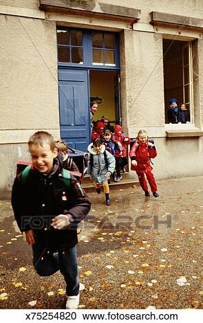Teacher Standing In Door Children Running Out Of Class Stock
