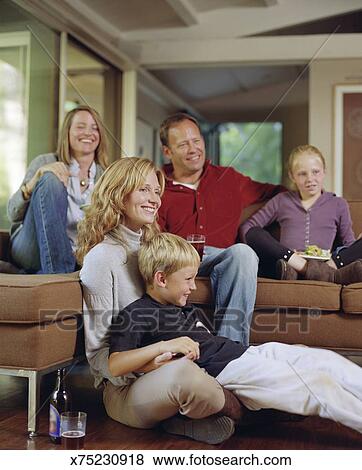 Family And Friends Sitting On Couch To Watch Tv Stock Photo