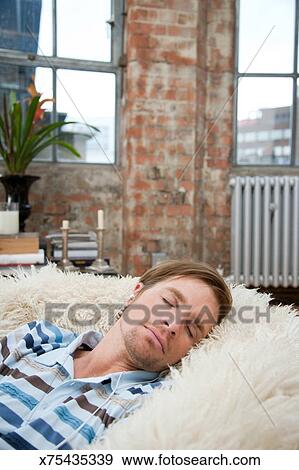 Man On A Furry Bean Bag Chair Wearing Earbuds Stock Photo