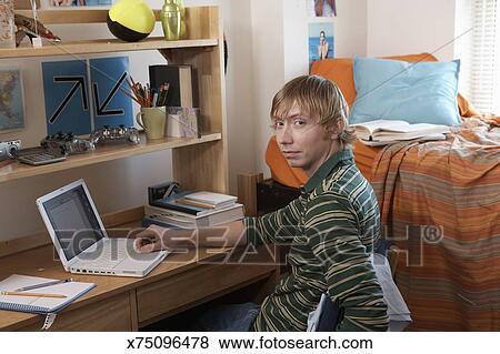 Young Man Smiling At Desk In Dorm Room Portrait Stock Photo