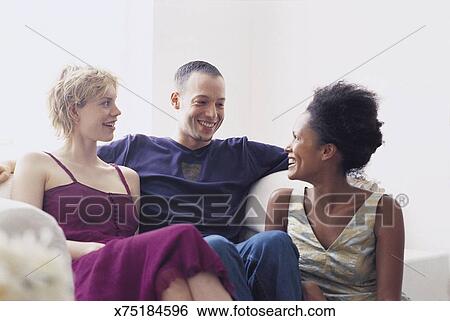 Two Women And A Man Sitting On Sofa Stock Photograph X75184596