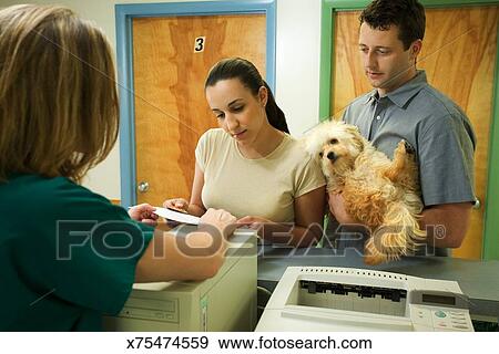 Couple With Dog At Front Desk Of Vet Clinic Stock Photo