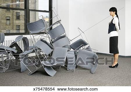 Young Woman Looking At Pile Chairs On Floor Side View Picture