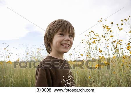 Boy standing in a field View Large Photo Image Stock Photo - Boy standing in a field. Fotosearch