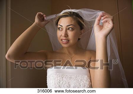 Bride lifting veil over head and looking out window View Large Photo Image Stock Photograph - Bride lifting veil over head and looking out window. Fotosearch
