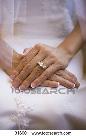 Stock Image - Close-up of bride’s hands and engagement ring. Fotosearch