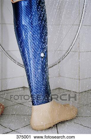 Stock Image - Low section of person standing in shower with prosthetic leg. Fotosearch