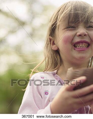 Young girl eating chocolate Easter egg and laughing View Large Photo Image Stock Image - Young girl eating chocolate Easter egg and laughing. Fotosearch