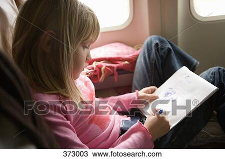 Young girl sitting in an airplane and drawing in a sketch pad View Large Photo Image Stock Image - Young girl sitting in an airplane and drawing in a sketch pad. Fotosearch