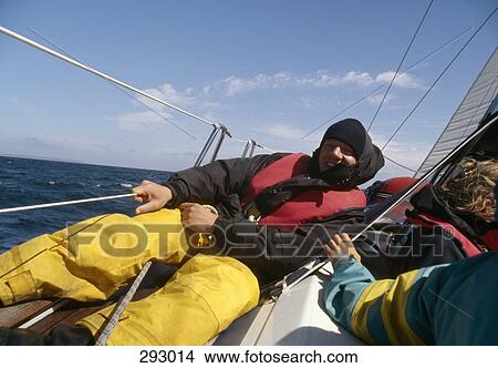 Young man sitting on deck of yacht and holding railing View Large Photo Image Picture - Young man sitting on deck of yacht and holding railing. Fotosearch