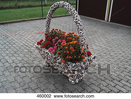 Stock Image - Geraniums in a decorative basket on a pavement. Fotosearch