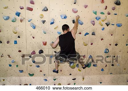 Stock Image - High angle view of a man indoor rock climbing. Fotosearch